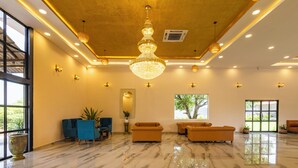 A spacious lobby with a marble floor, a large chandelier, and seating areas.