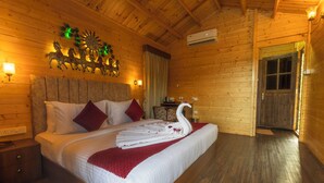 A wooden cabin bedroom with a bed, a nightstand, a wall-mounted clock, and a door.