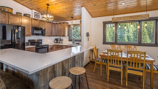 Une cuisine moderne avec des meubles en bois, un grand îlot central et un coin repas comprenant des chaises et une table en bois.
