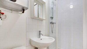 A bathroom with a white sink, a mirror, a shower, and a toilet. - A Canal St Martin Lovely Room (Paris)