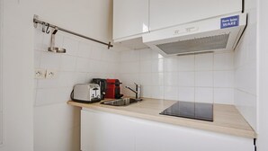 A small kitchenette with white cabinets, a stainless steel sink, a toaster, a red coffee maker, and a black electric kettle. - A Canal St Martin Lovely Room (Paris)