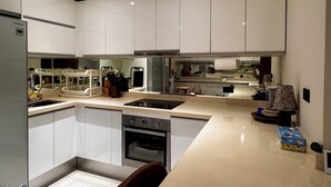 Une cuisine moderne avec des meubles blancs, un four encastré et un lave-vaisselle.