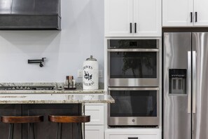 Una cocina moderna con electrodomésticos de acero inoxidable, armarios blancos y encimera de mármol.
