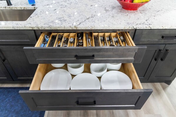 A kitchen drawer with utensils and plates.