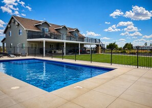 A residential property with a swimming pool, a covered patio, and a fenced yard.