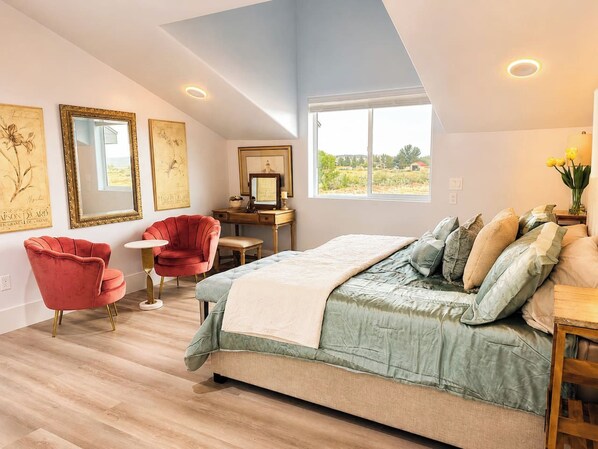A bedroom with a bed, a desk, a chair, and artwork on the walls.