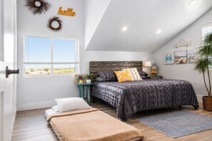A bedroom with a bed, bedside tables, a window, a door, and a wall with a 'hello' sign.