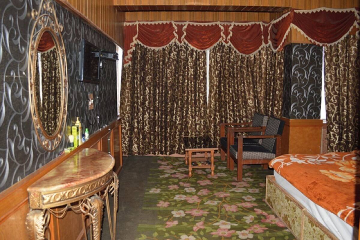 A room with a bed, a desk, a chair, a mirror, and curtains.