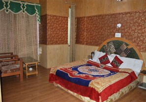 Um quarto com cama de madeira, uma mesa pequena e uma cadeira.