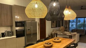 A modern kitchen with stainless steel appliances, a wooden dining table with two woven baskets, and pendant lights. - A3 - Sea view - Soleil des Canonniers (Trou-aux-Biches)