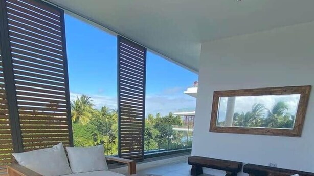 A modern outdoor living area with a sofa, two round wooden tables, and a bench. - A3 - Sea view - Soleil des Canonniers (Trou-aux-Biches)