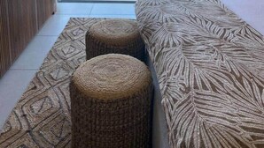 A bedroom with a large window, a bed with a leaf-patterned bedspread, and two woven ottomans. - A3 - Sea view - Soleil des Canonniers (Trou-aux-Biches)