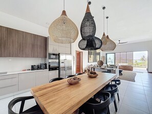 A modern kitchen with stainless steel appliances, a wooden dining table, and black chairs. - A3 - Ocean View - Soleil des Canonniers (Trou-aux-Biches)