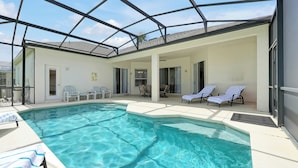Una piscina con sillas de descanso y un porche cubierto.