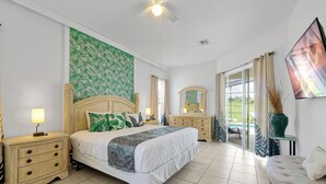 Un dormitorio con cama, mesitas de noche, cómoda y un ventanal con vistas al exterior.