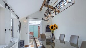 A dining area with a glass table, chairs, a vase with sunflowers, and a view to an outdoor patio. - 3 bedroom accommodation in Beccles (Beccles)