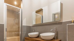A modern bathroom with a glass shower enclosure, two vessel sinks, and a wooden vanity. - New York Style Loft Apartment (Leith)