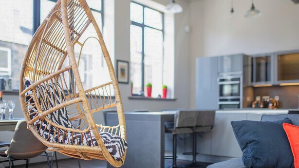 A modern interior with a hanging chair, a kitchen area, and a dining space. - New York Style Loft Apartment (Leith)