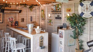 Zona de bar con paredes de madera, una barra y taburetes. Hay carteles en la pared, incluyendo uno que dice 
