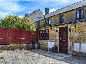 Un bâtiment en pierre avec une porte en bois, une clôture rouge et un panneau indiquant « PARCING POUR ARC».
