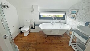 Ein Badezimmer mit freistehender Badewanne, Toilette und einer Duschkabine aus Glas.