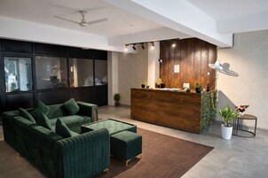 A modern reception area with a wooden desk, a green sofa, and a ceiling fan.
