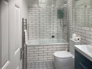 Une salle de bain moderne avec une douche à parois de verre, des toilettes blanches et un meuble-lavabo avec un miroir.