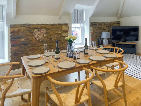 Un coin repas avec un mur en pierre, une table en bois et des chaises.
