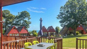 Eine Terrasse mit Tisch und Stühlen, mit Blick auf eine Reihe von Häusern mit roten Dächern und einen klaren Himmel.