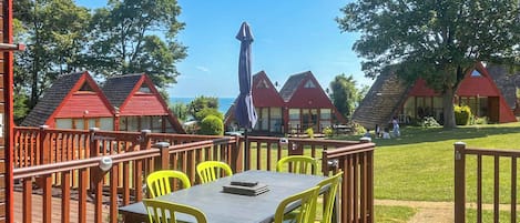 A deck with a table and chairs, overlooking a row of red-roofed cottages and a clear sky.