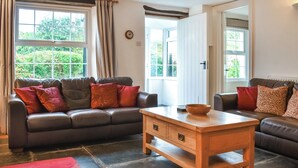 A living room with two sofas, a wooden coffee table, and a red rug. - 3 bedroom accommodation in Bude (Bude)
