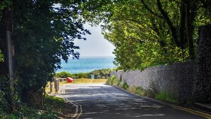 A paved road with a stone wall on one side and a view of the sea on the other.