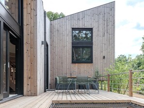 A modern building with a wooden exterior, a deck with outdoor seating, and a large window. - Unique design holiday home in a quiet location (Biron)