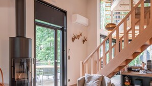 Een moderne woonkamer met een grote open haard, een trap en uitzicht op de omgeving.