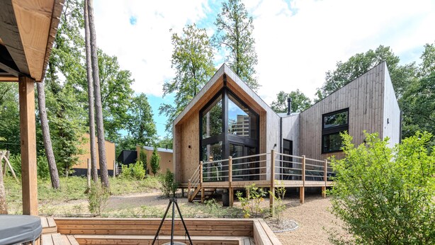 Een moderne houten blokhut met een grote glazen deur, een jacuzzi en een terras.