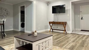 Un salon moderne avec un téléviseur à écran plat, une table basse en bois et un téléviseur fixé au mur.