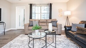 Ein Wohnzimmer mit einer Couch, zwei Couchtischen, einer Stehlampe und einem Deckenventilator.