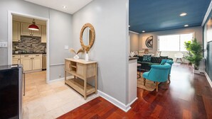Una cocina moderna con armarios de madera, una lámpara colgante roja y un espejo redondo sobre una consola.