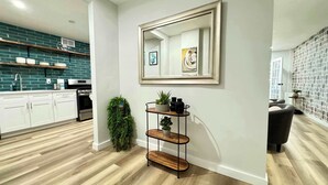 A modern kitchen with white cabinets, a stainless steel oven, and a teal backsplash.