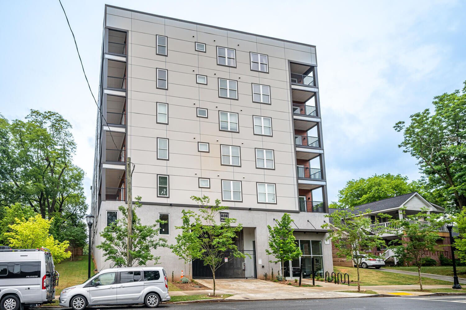 A multi-story residential building with a flat facade, multiple balconies, and a gated entrance.