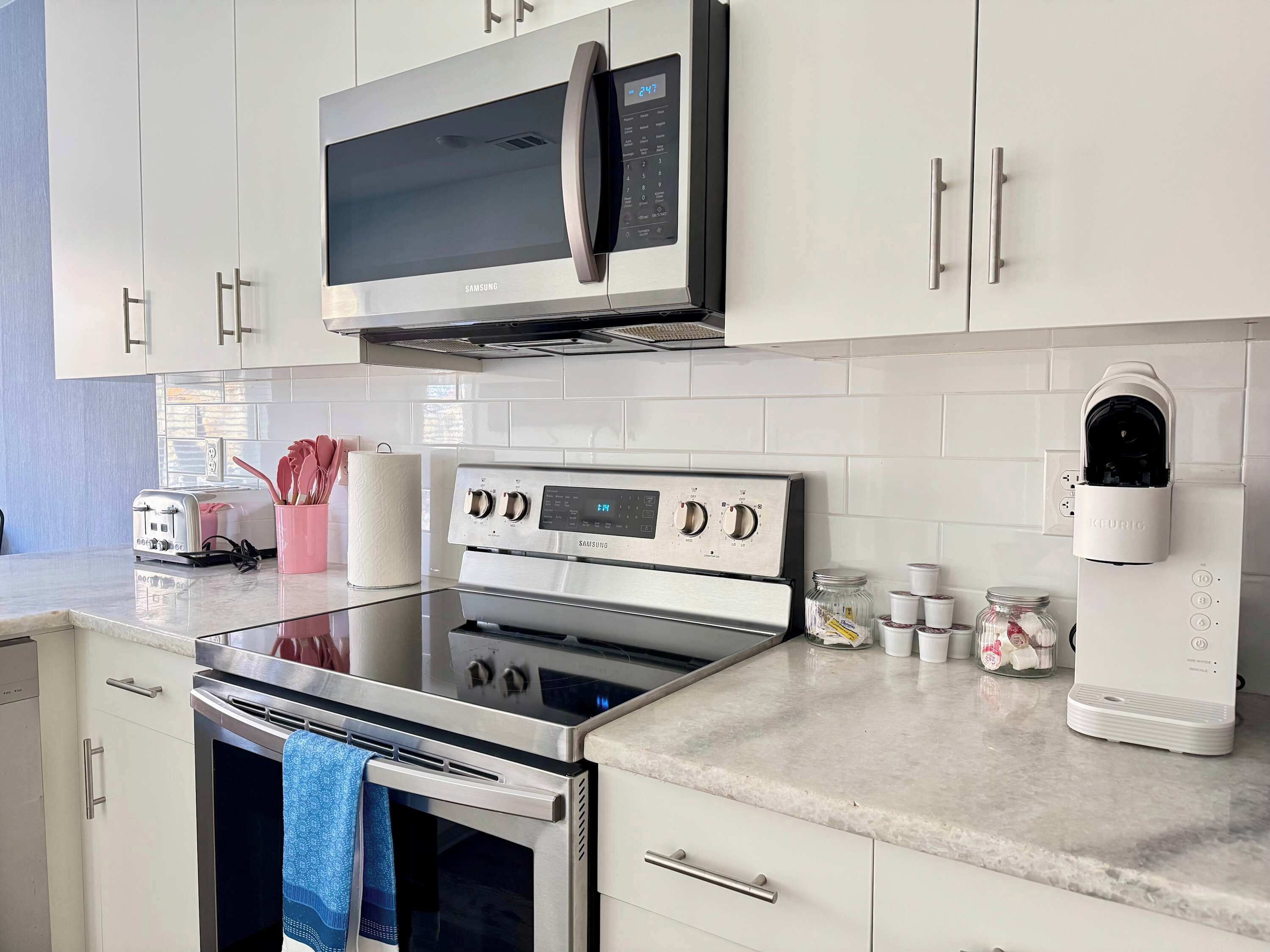 Uma cozinha moderna com eletrodomésticos de aço inoxidável, incluindo micro-ondas, forno e cafeteira.