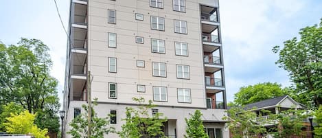 A multi-story residential building with a flat facade, multiple balconies, and a gated entrance.