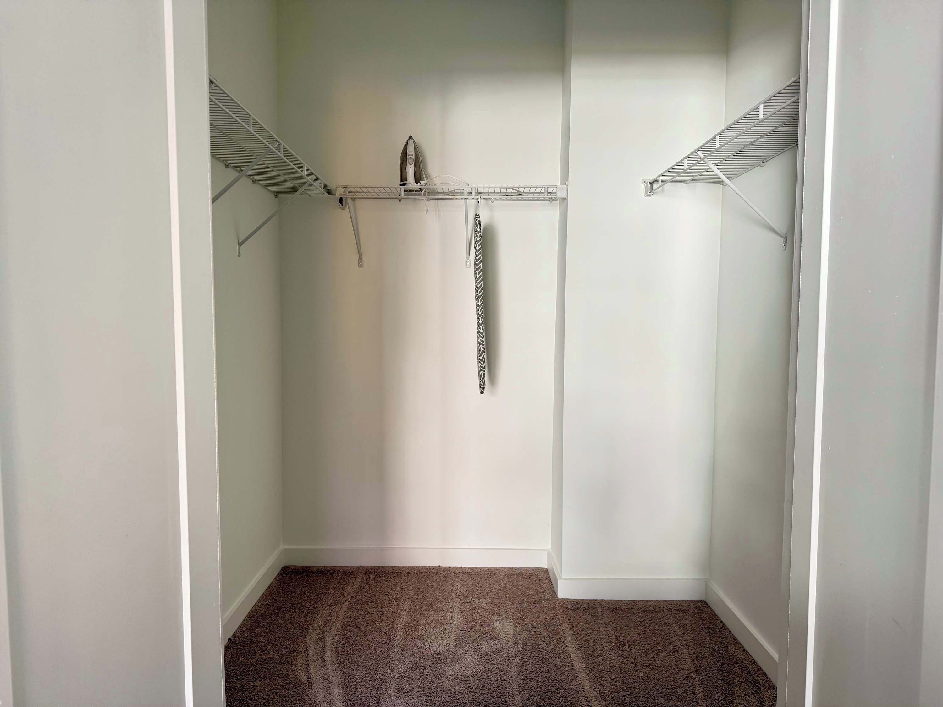 A walk-in closet with a hanging rack and a shoe rack.