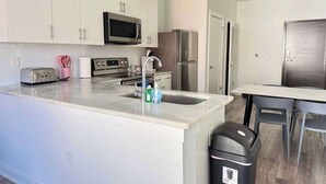 A modern kitchen with white cabinets, stainless steel appliances, a built-in microwave, a stainless steel refrigerator, and a sink with a faucet.