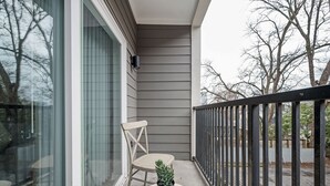 A balcony with a chair, a potted plant, and a glass door. - Upgraded Apartment in Old Fourth Ward (Atlanta)