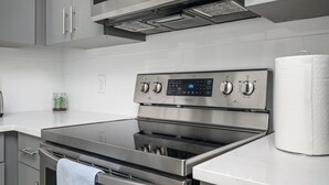 A modern kitchen with stainless steel appliances, a digital control panel, and a white countertop. - Upgraded Apartment in Old Fourth Ward (Atlanta)