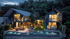 A modern two-story house with a large outdoor swimming pool, multiple balconies, and lush greenery surrounding the property. - Hin Butik Villa 4BR Private Seaview (Koh Samui)