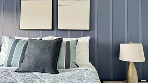 A bed with patterned bedding, a bedside lamp, and two framed artworks on a wall.