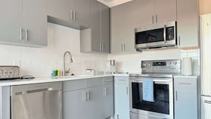 A modern kitchen with grey cabinets, a stainless steel dishwasher, a built-in oven, and a microwave.