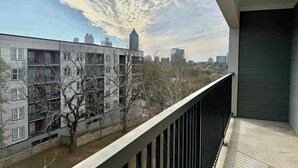Ein Balkon mit Blick auf eine Stadtlandschaft, darunter ein hoher Gebäudebau und Wohngebäude.